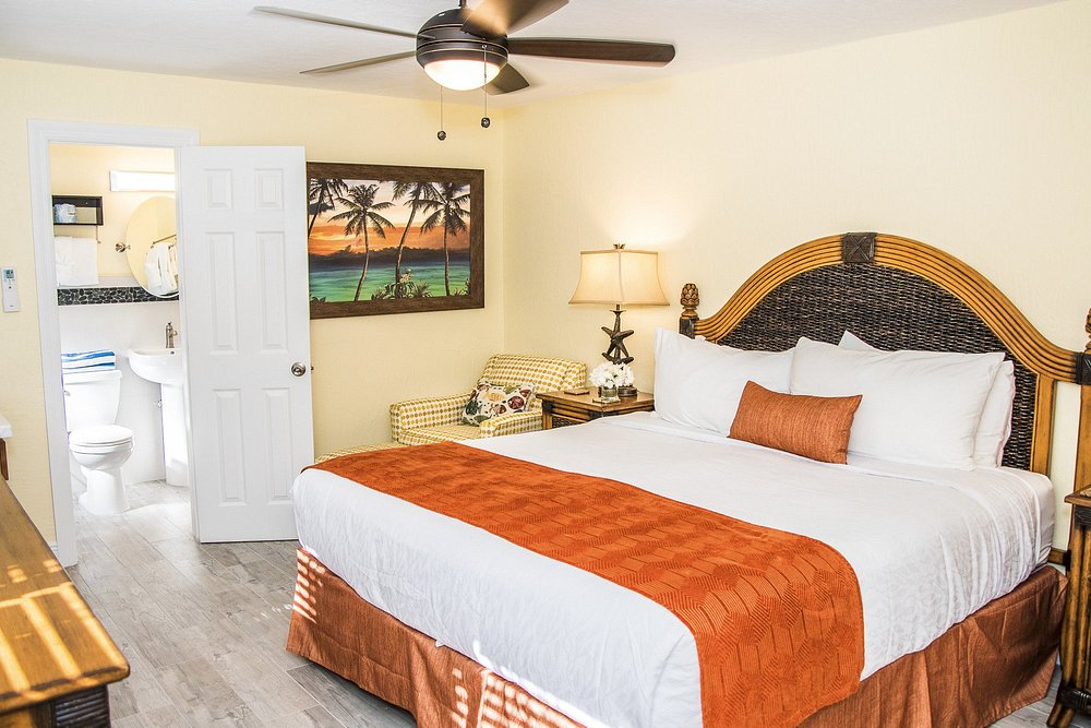 King guest room with woven headboard and orange accent throw